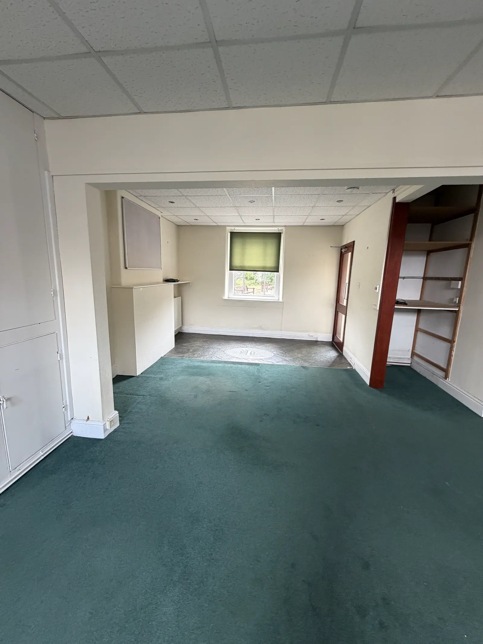 The ground-floor rear office today: green carpet and a window onto the yard