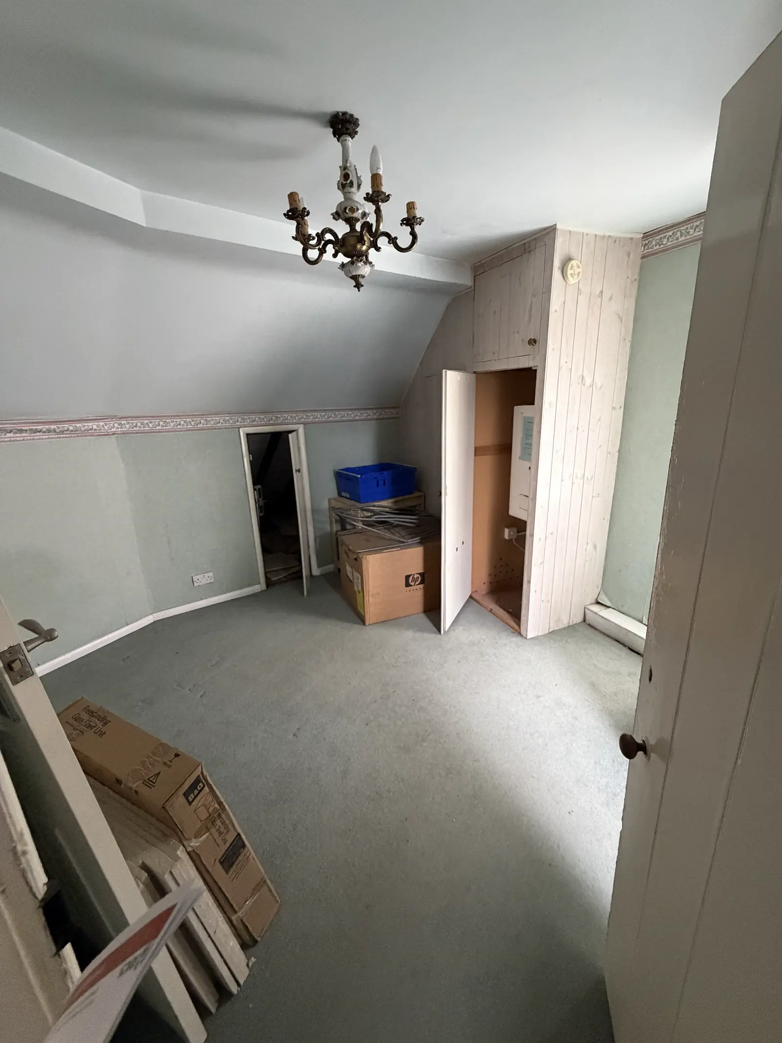 An attic room on the second floor with a chandelier and stored boxes